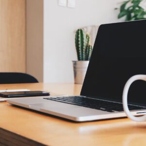Laptop used to do chemical hygiene plan authoring on desk with mobile phone and coffee cup